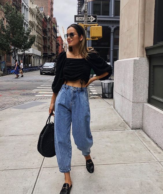 chica rubia con lentes de sol, blusa negra, bolso negro, jeans slouchy y flats de piel