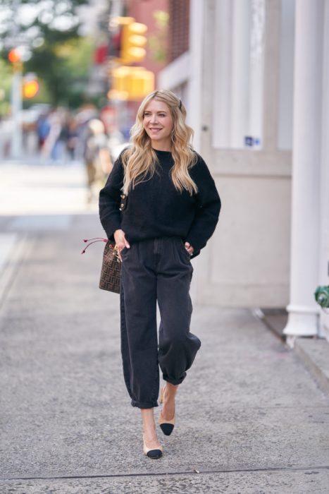 chica rubia con suéter negro, jeans slouchy negros y flats