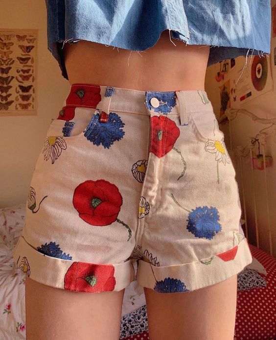 chica llevando short corto en blanco con flores azules y rojas