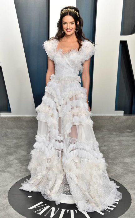 Lydia Hears usando un vestido blanco con encajes durante el after party de los premios Oscar 2020