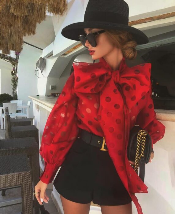 Victoria Fox usando shorts negros y sombrero a juego, con blusa roja