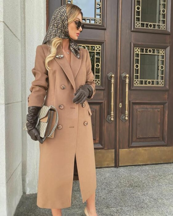Victoria Fox usando abrigo color camel y pañuelo sobre la cabeza