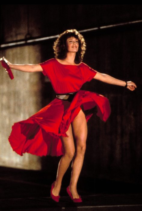 Kelly LeBrock en La mujer de rojo caminando por la calle mientras su vestido de color rojo vuela 