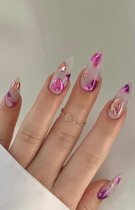 Uñas transparentes decoradas con corazones brillantes en color rosa