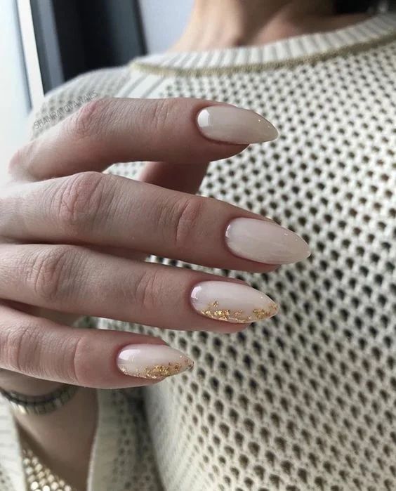 Uñas blancas con punta de almendra y detalles dorados en los bordes
