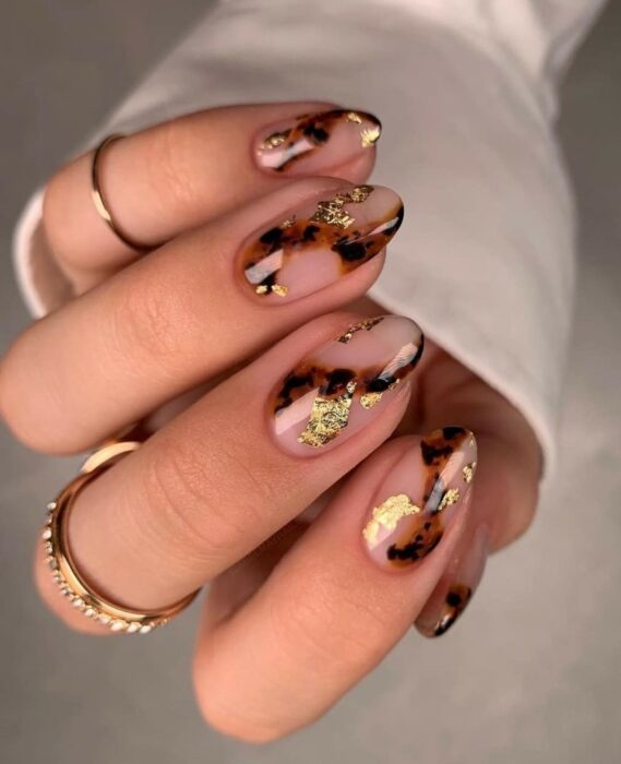 Uñas elegantes ovaladas con detalles dorados y animal print