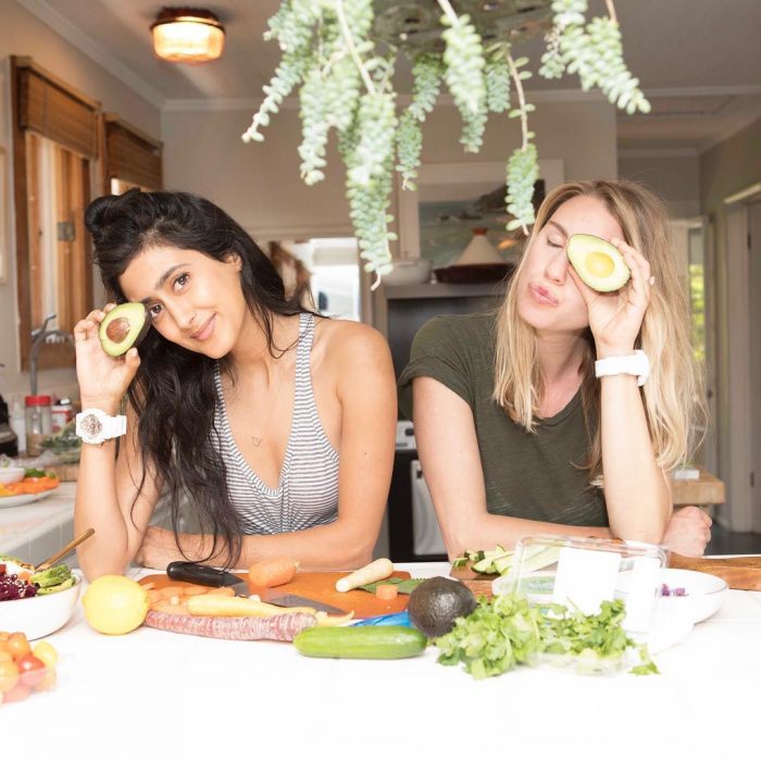 Chicas comiendo aguacates dentro de una cocina blanca
