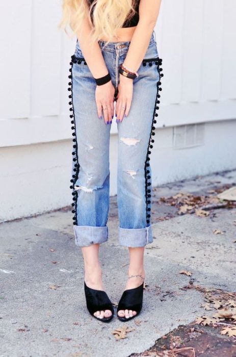 Jeans deslavados con pompones negros en los costados