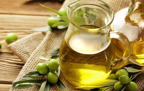 Jarra de cristal con aceite de oliva sobre una tabla de madera