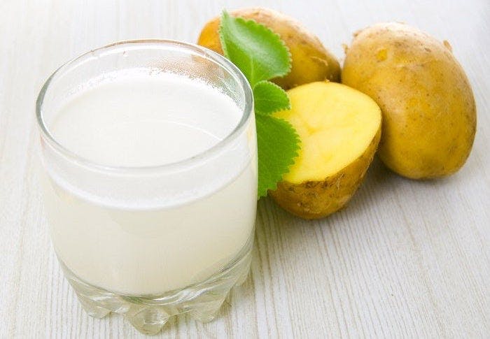 Vaso de cristal con jugo de papa en el interior