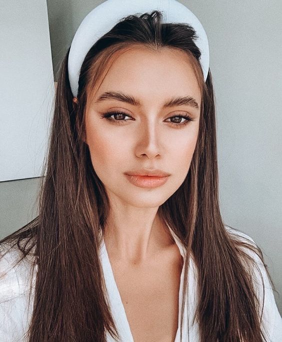 Chica delgada de cabello castaño lacio y suelto con diadema blanca