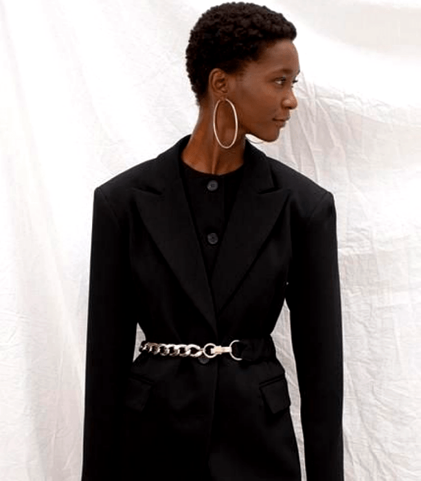 chica morena con traje negro de vestir formal con cinturón metálico plateado