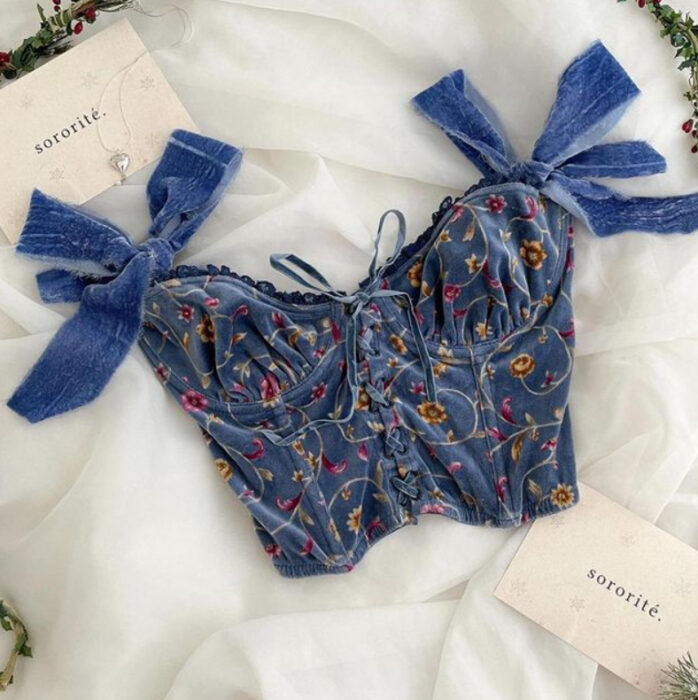 Corsé de color azul, con estampado de florecitas de colores y moños en el inicio de los hombros