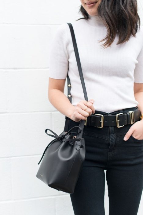 Chica usando top blanco con jeans negros y bucket bag negra