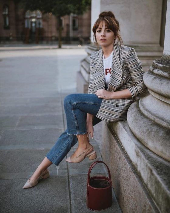Chica usando jeans con camiseta blanca, blazer de cuadros y bucket bag color café