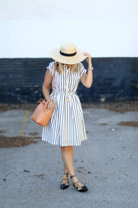 Chica usando vestido a rayas con sombrero y bucket bag color camel
