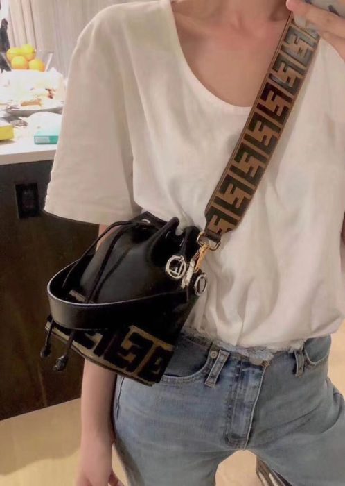 Chica usando mom jeans con camisa oversized y bucket bag pequeña negra