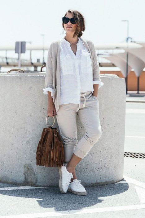 Chica usando joggers y suéter beige con camisa blanca y bucket bag de gamuza color café