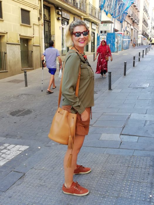 Chica usando bermudas con sudadera verde olivo y bucket bag color camel