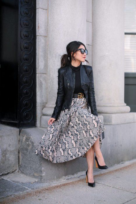 Chica usando chaqueta de cuero negra con maxi falda de estampado y blusa negra