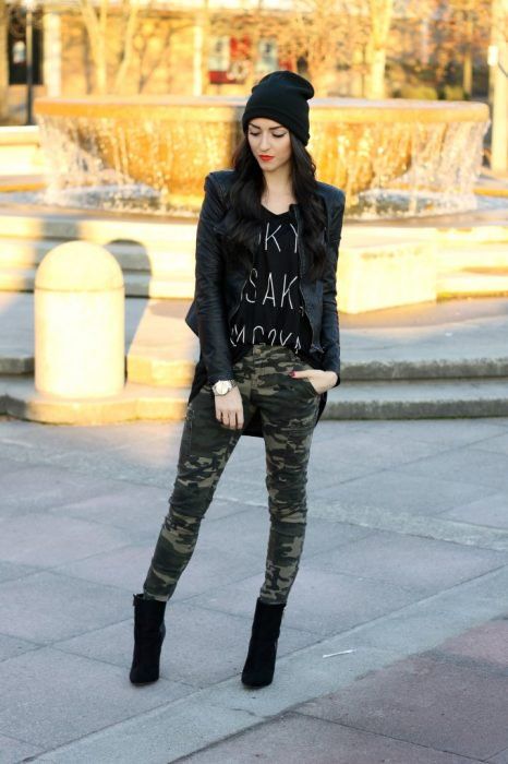 Chica usando chaqueta de cuero negra con botines negros, pantalón de estampado militar y blusa negra