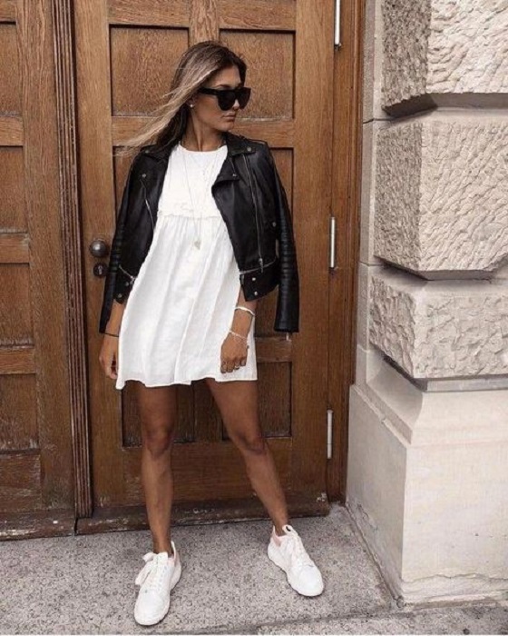 Chica usando chaqueta de cuero negra con vestido blanco y tenis del mismo color