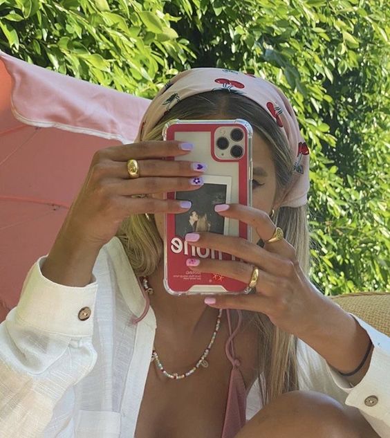 Chica rubia tomándose selfie tapando su rostro y usando un pañuelo con estampado de cereza en la cabeza