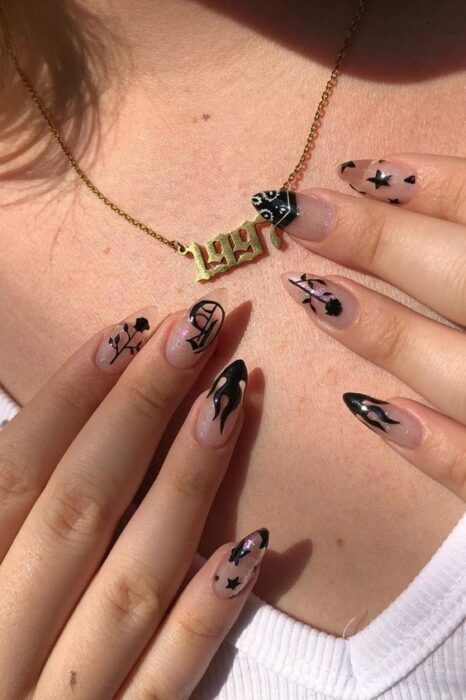 Chica usando cadena dorada con número 1997 apoyando sus uñas acrílicas largas con detalles negros