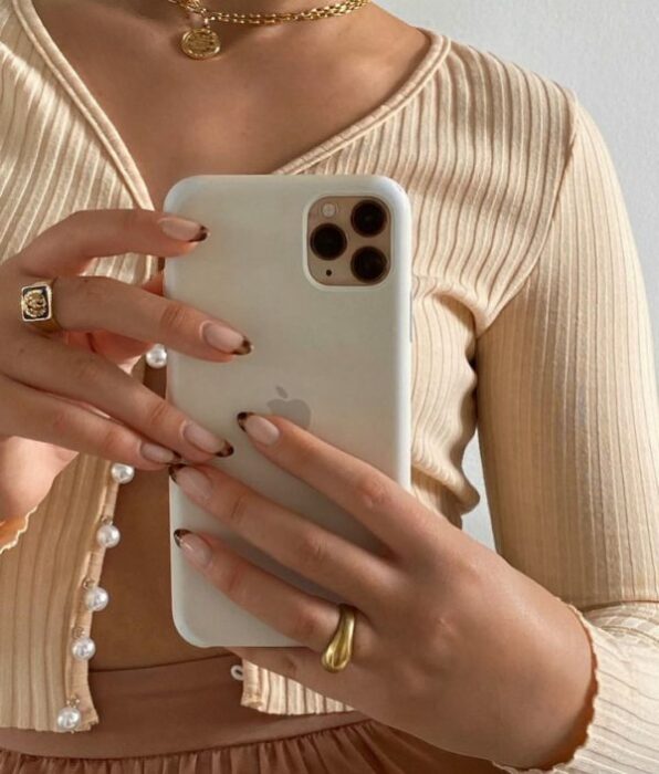 Chica tomándose selfie con iPhone sujetándolo con uñas con punta de animal print