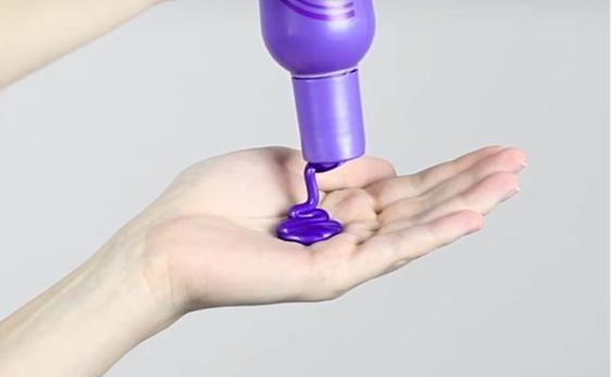 Persona sosteniendo champú morado en la palma de la mano