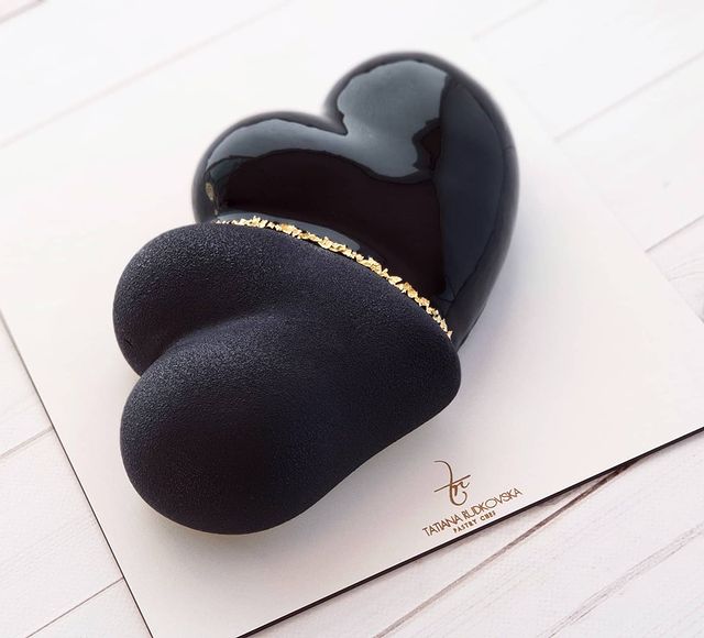 Pastel de chocolate en forma de corazón con betún negro y decoraciones en dorado