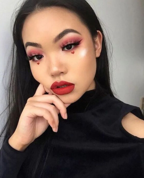Maquillaje inspirado en San Valentín en colores rojo y guinda con corazones debajo de los ojos