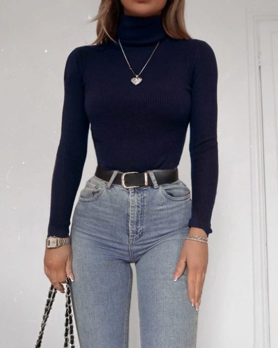 Chica con jeans de tiro alto denim, cinturón negro y blusa de manga larga y cuello alto negra
