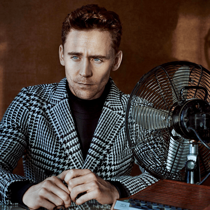 tom hiddleston con camiseta negra de manga larga y abrigo saco gris de cuadros