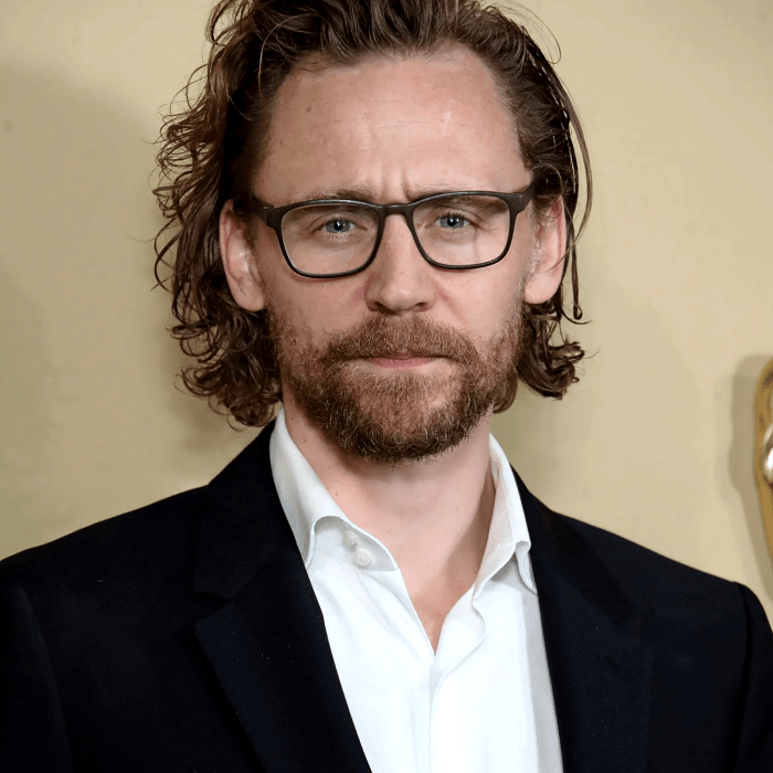 tom hiddleston con lentes, camisa blanca, saco negro