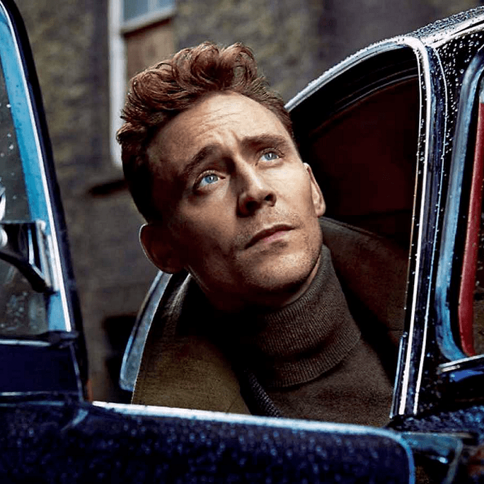 tom hiddleston rubio con suéter café de cuello alto y chamarra café