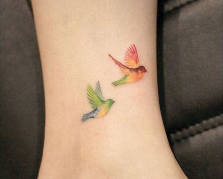 Tatuaje pequeño sobre el tobillo de dos golondrinas