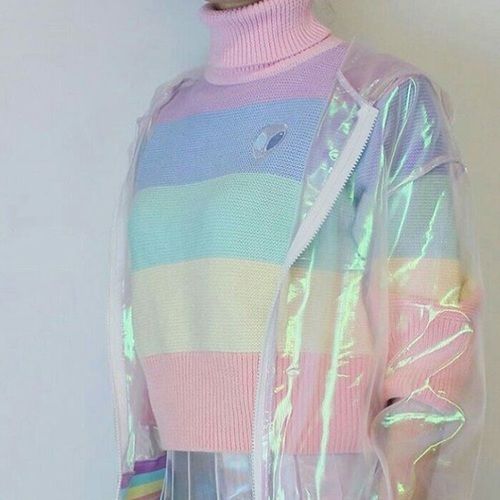 Mujer usando suéter de rayas gruesas en tonos pastel con estampado de marcianito y encima una chamarra transparente con efecto tornasol