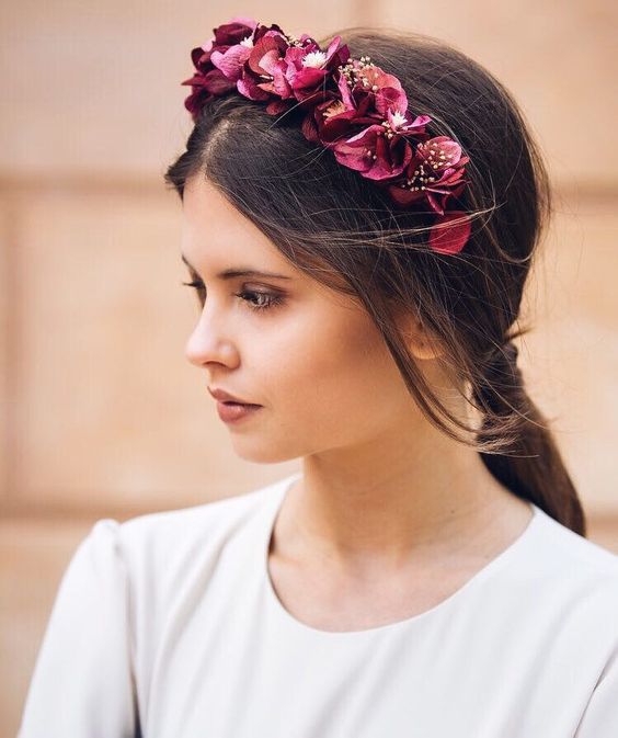 Chica con melena larga y castaña con diadema roja con flores
