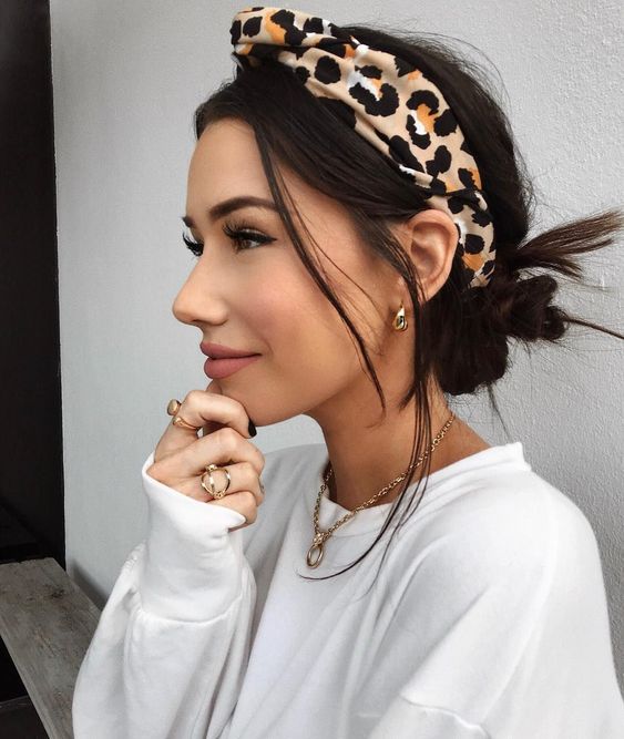 Chica morena con chongo bajo despeinado y banda de cabello en animal print