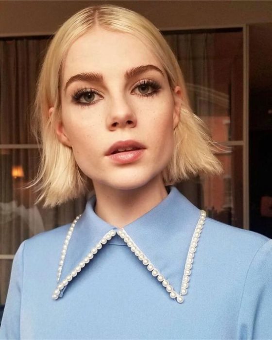Lucy Boynton con blusa azul y cuello bobo con perlas