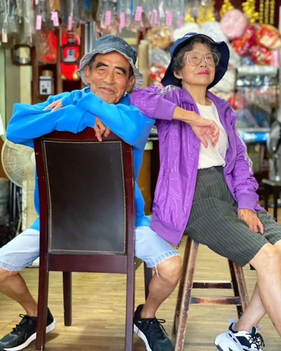 Pareja de abuelitos sentados en bancos de madera usando sombreros estilo pescador a juego