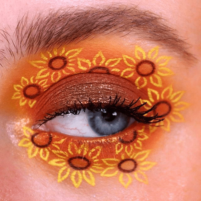 maquillaje de ojos con sombreado naranja y amarillo y dibujos de girasoles amarillos y naranjas