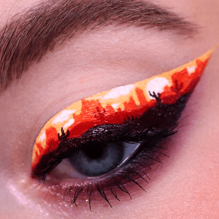 maquillaje de ojos con delineado negro con naranja y blanco, recreando un paisaje