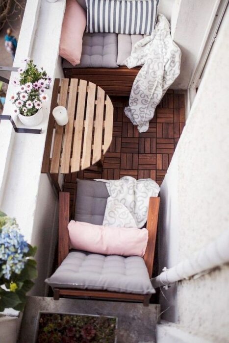 Decoración de terraza en tonos rosas y blancos, con elementos de madera