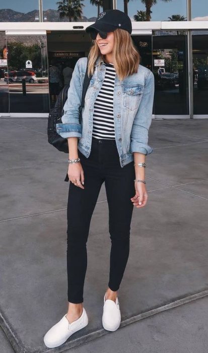 Chica con pantalón negro, blusa de rayas y chamarra de mezclilla con tenis blancos