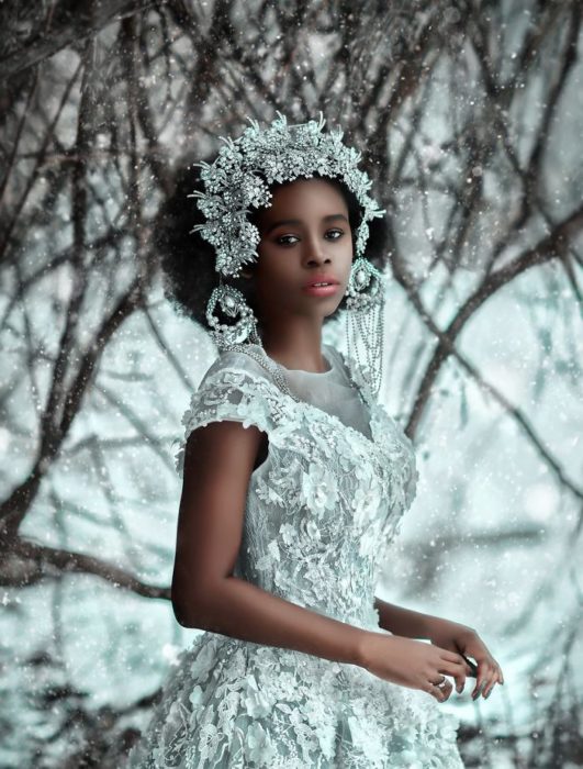 Chica negra en la nieve con vestido plateado y tocado