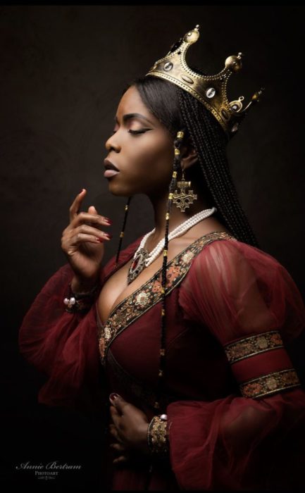Chica negra con vestido rojo de reina y corona dorada