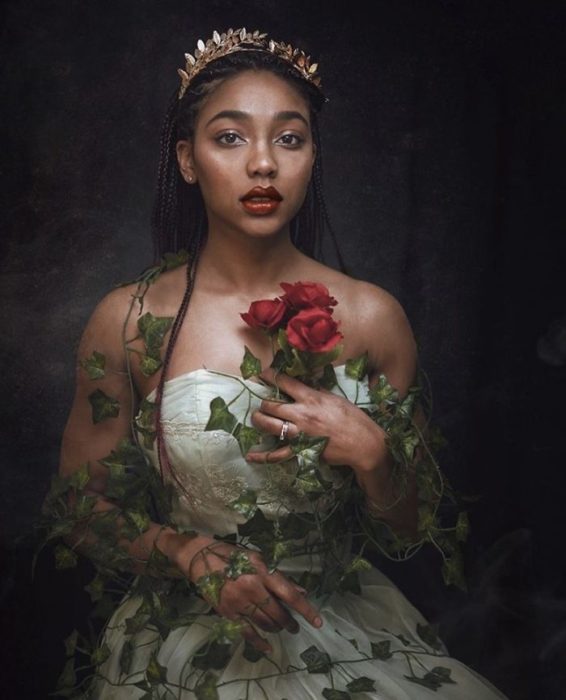 Chica negra con tiara y velo en la cabeza, con vestido blanco y sosteniendo una rosa roja