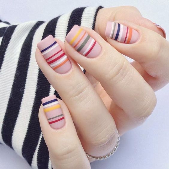 Manicura en tono carne con líneas de colores